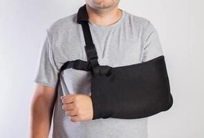 A man on a white background in a bandage to support his arm. Immobilization of the hand and forearm after injury. Rehabilitation after a broken bone. Orthopedics photo