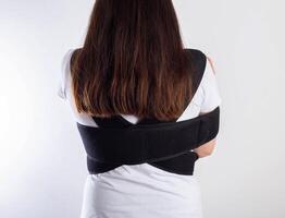 A girl in a medical brace on the shoulder joint for rehabilitation after a collarbone fracture and dislocation. Shoulder sprain, acromioclavicular joint photo
