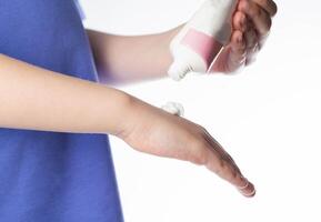 The hands of a girl apply a medicinal cream against chapping of the skin on a white background. Moisturizing and protective hand cream, close-up photo
