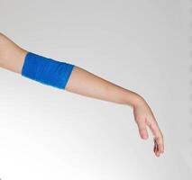 Blue elastic bandage on the elbow joint of the child on the arm. White background, close-up. Hand pain photo