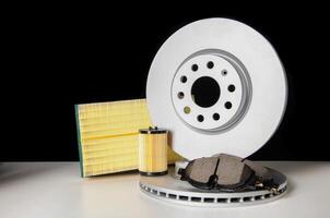 Set of car auto parts on a black background. Brake discs with pads, air and oil filter. Copy space for text, industry photo