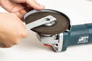 The worker spins the cleaning disk in the grinder with a special key before starting work. photo