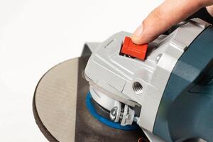 Modern angle grinder with red spindle lock button. Close-up, smooth start. photo