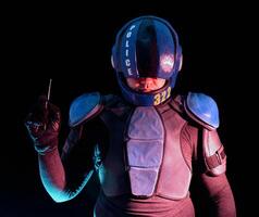 Cyberpunk concept, world of the future. Police officer in the dark, half-human, bionic cyborg holds his hand with a remote control from a bomb explosive. The stand looks into the camera in the dark. photo
