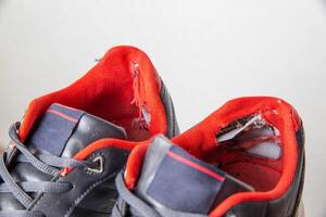 Torn backs in multicolored sports sneakers on a white background, isolate. Poor quality shoes. Copy space for text, macro photo