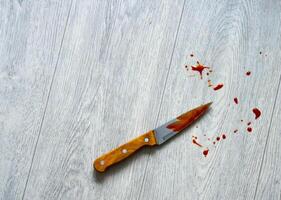 The blade of the knife in the blood lies on the floor. Stabbing and injury, crime. Aggression. Copy space for text photo