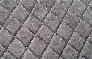 Factory fabric with stitched stitching in the form of gray diamonds. Background, close-up photo