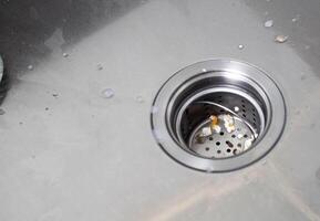 Protective mesh filter in a metal sink in the kitchen from blockage. Clogged sink with food particles after washing dishes. Copy space for text photo