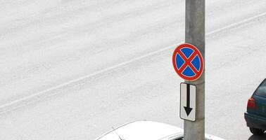 Stop and parking prohibited road sign hangs on a pole against the background of a road with cars. Violation of traffic rules, parking problem. Copy space for text photo