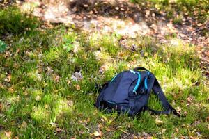 The man's backpack lies on the grass in the forest. Missing person concept. An accident in the forest. Lost mushroom picker. Attack of a wild animal. Fatal outcome. Copy space for text photo