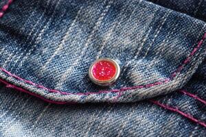Blue denim, background. Stylish jeans, macro, design. Red button photo