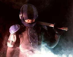 Cyberpunk future concept. Bionic cyborg police officer with short samurai sword stands in dark with smoke, fume. Halfman robot looks at camera. Futuristic science fiction scene. photo