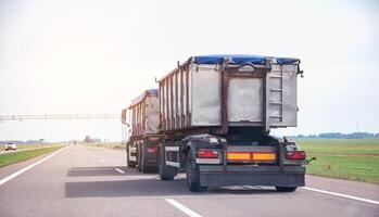 Transportation of grain in a dump truck with a trailer covered with an awning on the road. Agribusiness, copy space for text photo