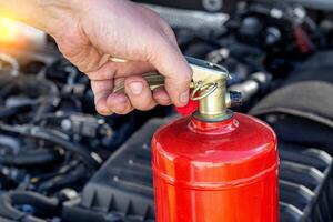 Car fire extinguisher on the background of the car engine. Extinguishing class of fire extinguisher, expiration date. Copy space for text photo