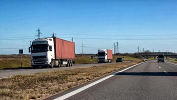 A convoy of two trucks with container trailers transports heavy containers from the seaport. The concept of logistics companies transporting goods from the port. Copy space for text photo