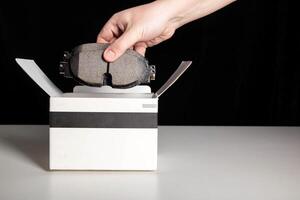 The mechanic takes out new car brake pads to replace them. Black background, copy space for text photo
