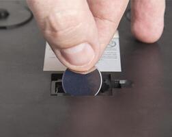 Installing a new round coin cell battery in an electrical appliance. Replacing a dead battery, macro. photo