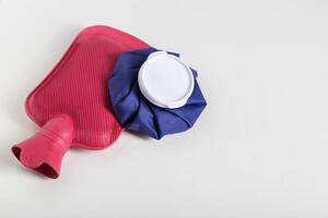 Red medical water heater and blue ice bag on a white background. The concept of treating diseases with heat and cold, heat therapy. Copy space for text photo