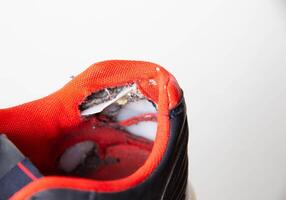 Torn backs in multicolored sports sneakers on a white background, isolate. Poor quality shoes. Copy space for text, macro photo