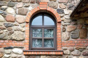An old wooden semicircular window lined with bricks in a stone building. Architectural, close-up photo