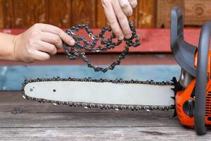 New chain for chainsaw. Setting up and replacing the chain on the chainsaw from the old to the new. Chain sharpening. Industry photo