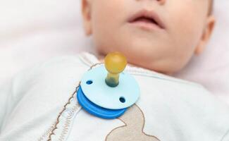 Little caucasian baby boy and pacifier. The habit of the sucking reflex in infants. photo