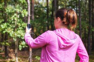 A girl in a pink sweater uses a navigator in the forest to determine her location. Mushroom picker and compass. Wandering through the forest, signal gps photo