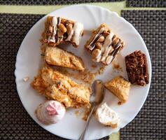 Leftovers in a plate on the table with sweets cakes, close-up photo