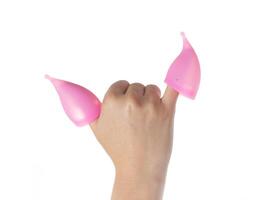 Two menstrual cups put on female fingers on a white background. Hygienic vaginal cups for collecting discharge during menstruation, close-up, isolate photo