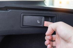 Button for folding and unfolding the rear row of seats in a passenger car, close-up photo