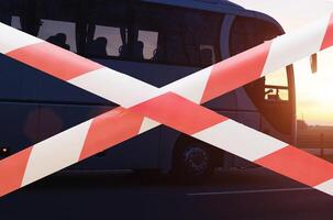 Forbidden tape on the background of a travel company passenger bus. The concept of loss and closure of tour operators during the coronavirus pandemic, bankrupt. Closing state borders, traveling photo
