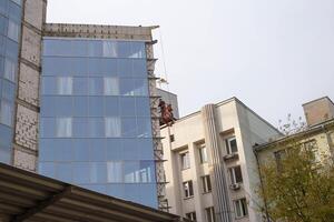 A man insulates the walls of a building with a modern ventilated facade. The concept of frost resistance and sound insulation, protection photo