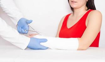 Doctor traumatologist cuts a plaster cast of a young girl on her arm with a fracture of the radius without displacement, copy space photo