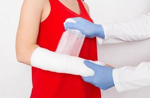 Doctor surgeon wraps the arm with a bandage of a girl whose sprain and pain in the arm, deforming arthrosis photo