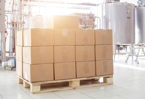 Boxes with finished dairy products at the factory on the background of production equipment. The concept of the production of milk and sour cream, the manufacture of glazed curds and butter photo