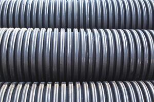 Large diameter black polypropylene pipes for laying communications, drainage systems and heating mains under the road. Modern method and technology for supplying water and sewage, copy space, industry photo
