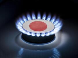 Burning gas burner of a home stove in the middle of which is the flag of the country of Japan. Gas import and export delivery concept, price per cubic meter, transit, background photo