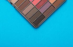 A set of modern eye shadows with powdery shades on a blue background. Soft texture and shading, brand, close-up. Copy space for text photo