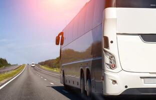 New modern passenger bus on the road in summer against the blue sky. The concept of passenger transportation and traveling around the countries by bus. Copy space for text photo