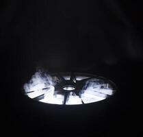A modern beautiful automotive alloy wheel in the form of rays that is highlighted by rays of light and brilliance. Stylish cast smoke, industry photo