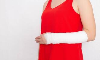 Girl in a red T-shirt with a broken arm in a tight bandage and plaster on a white background. Radial Fracture Treatment Concept, copy space photo