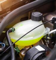Car reservoir for filling coolant. Yellow antifreeze in the expansion tank, freezing temperature concept in winter. photo