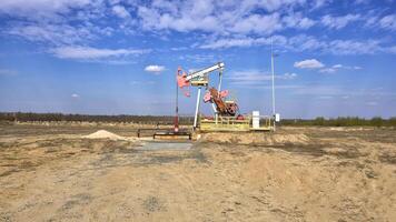 Oil and gas well in the field against the background of clouds and blue sky, industry, copy space for text photo