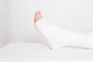 Ankle wound with a bandage in a tight fixing bandage on a white background. Concept of leg fracture and plaster bandage, hospital photo