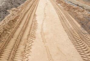 Track from the wheels of construction equipment and a truck on the sand, background, copy space photo