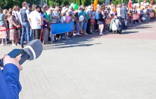 hands of a reporter with a microphone on the background of a crowd of people. Interview and news concept, Copy space for text photo