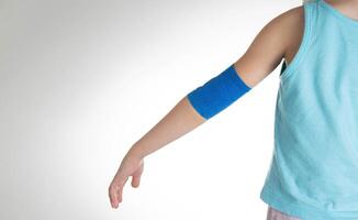 Blue elastic bandage on the elbow joint of the child on the arm. White background, close-up. Hand pain photo