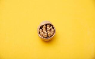 Walnut with broken shells on a yellow background, close-up. Walnut resembling a human brain photo