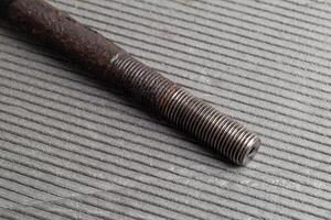 Old rusty steering rod on a gray background, close-up. photo