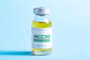 Vial with coronavirus vaccine on blue background, close-up. Vaccination of the population against coronavirus, SARS-Cov-2 photo
